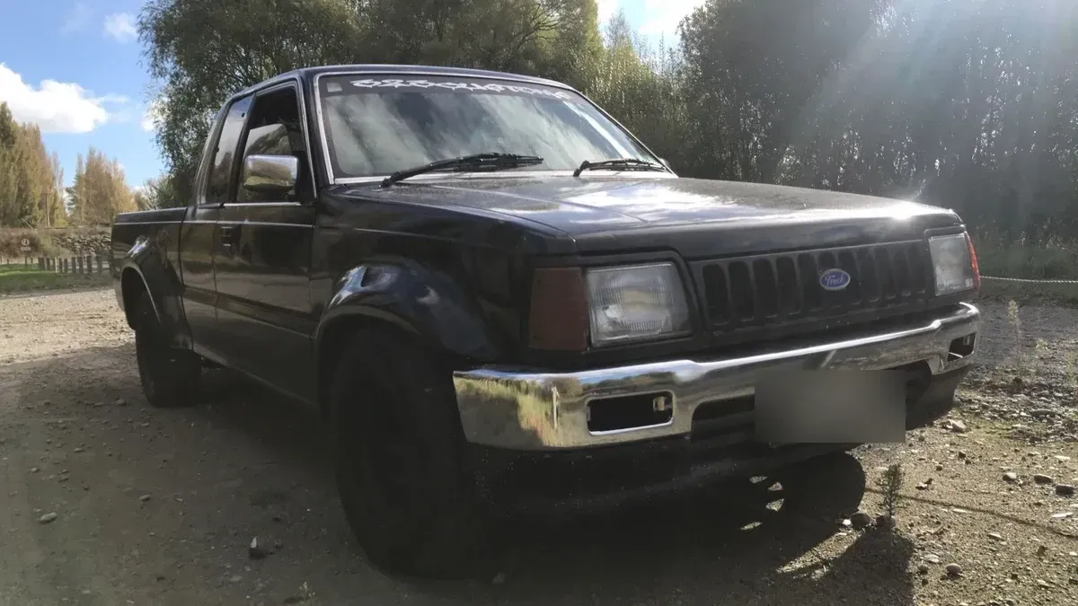 A Ford Courier ute in tired black paint before restoration