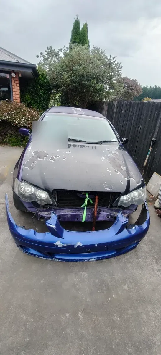 A Ford Falcon with peeling paint and the front bumper stripped off