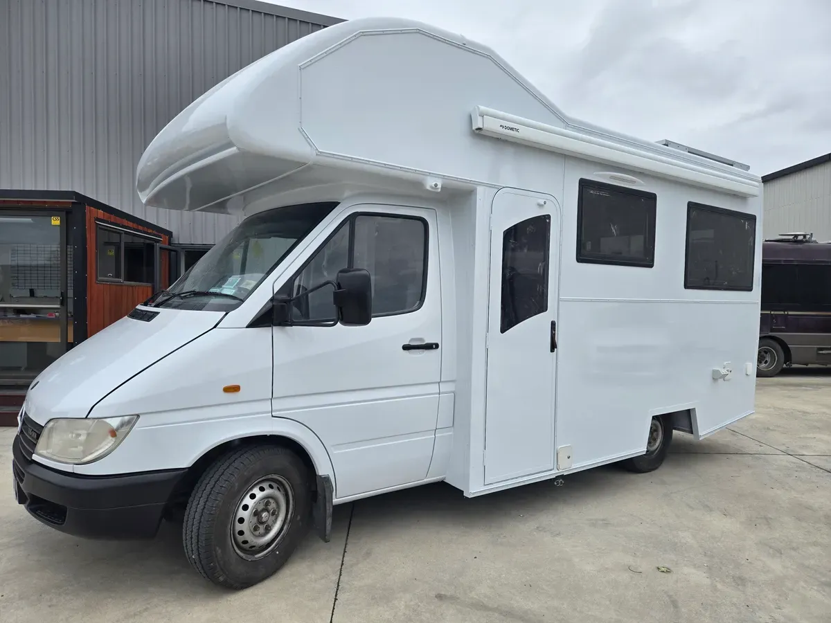 A motorhome resprayed gloss white outside the workshop