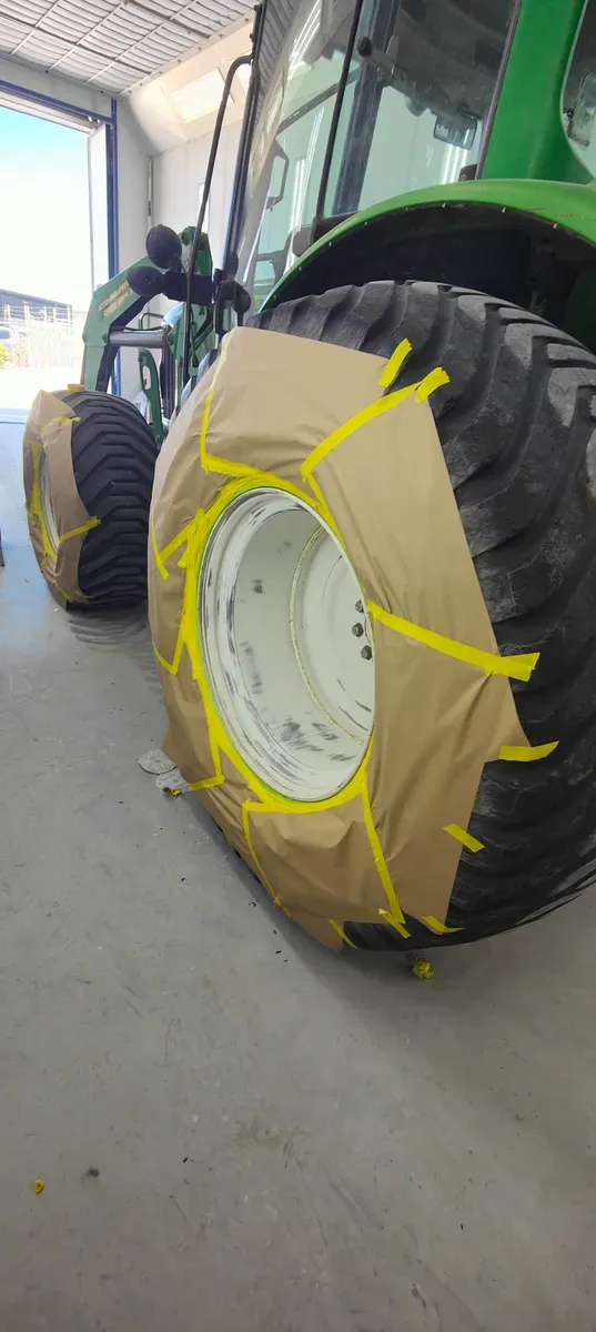 A John Deere tractor masked up for paint in the spray booth